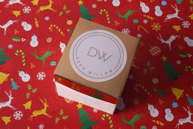 Elegant gift box with a custom logo sticker surrounded by festive Christmas prints